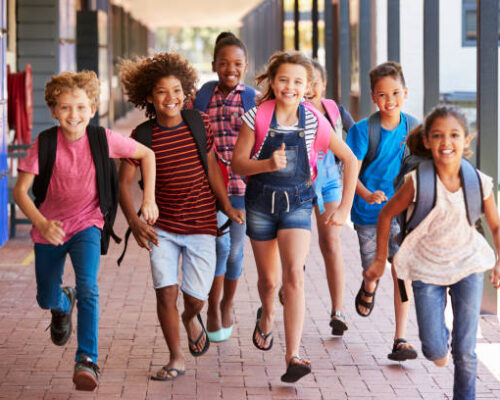 School kids running in elementary school hallway, front view